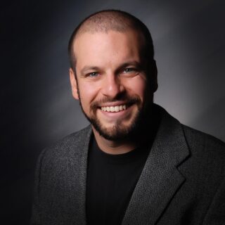 A photo of Logan Cohen is captured. He is a Licensed Marriage and Family Therapist (LMFT), an Approved Supervisor with the American Association of Marriage & Family Therapy (AAMFT), and a Level 2 Clinical Certified Trauma Professional (CCTP-II). Logan is featured on Grow a Group, a therapist podcast.